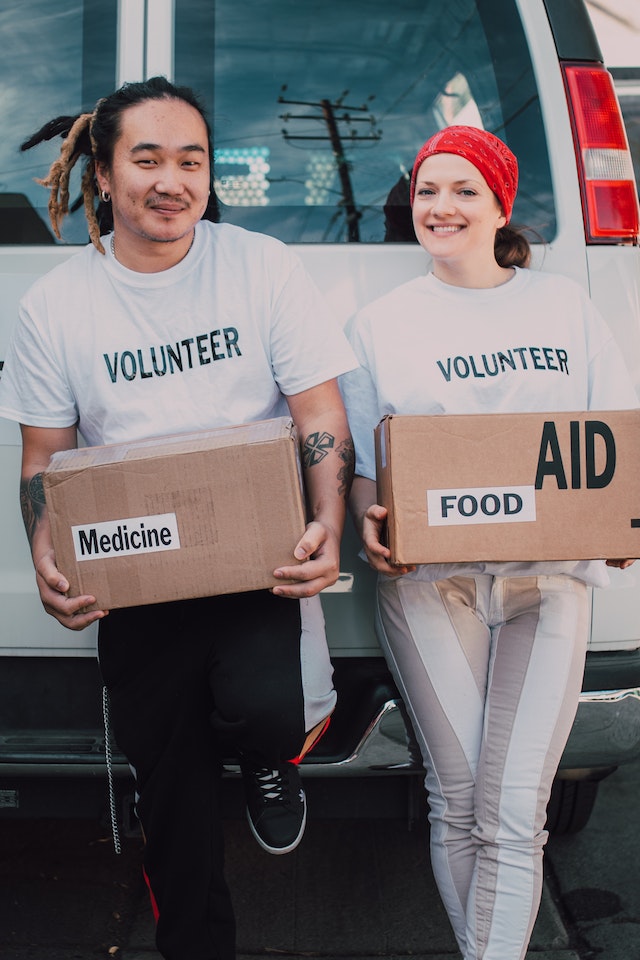 un ragazzo ed una ragazza volontari hanno in mano due scatole di cibo e medicine